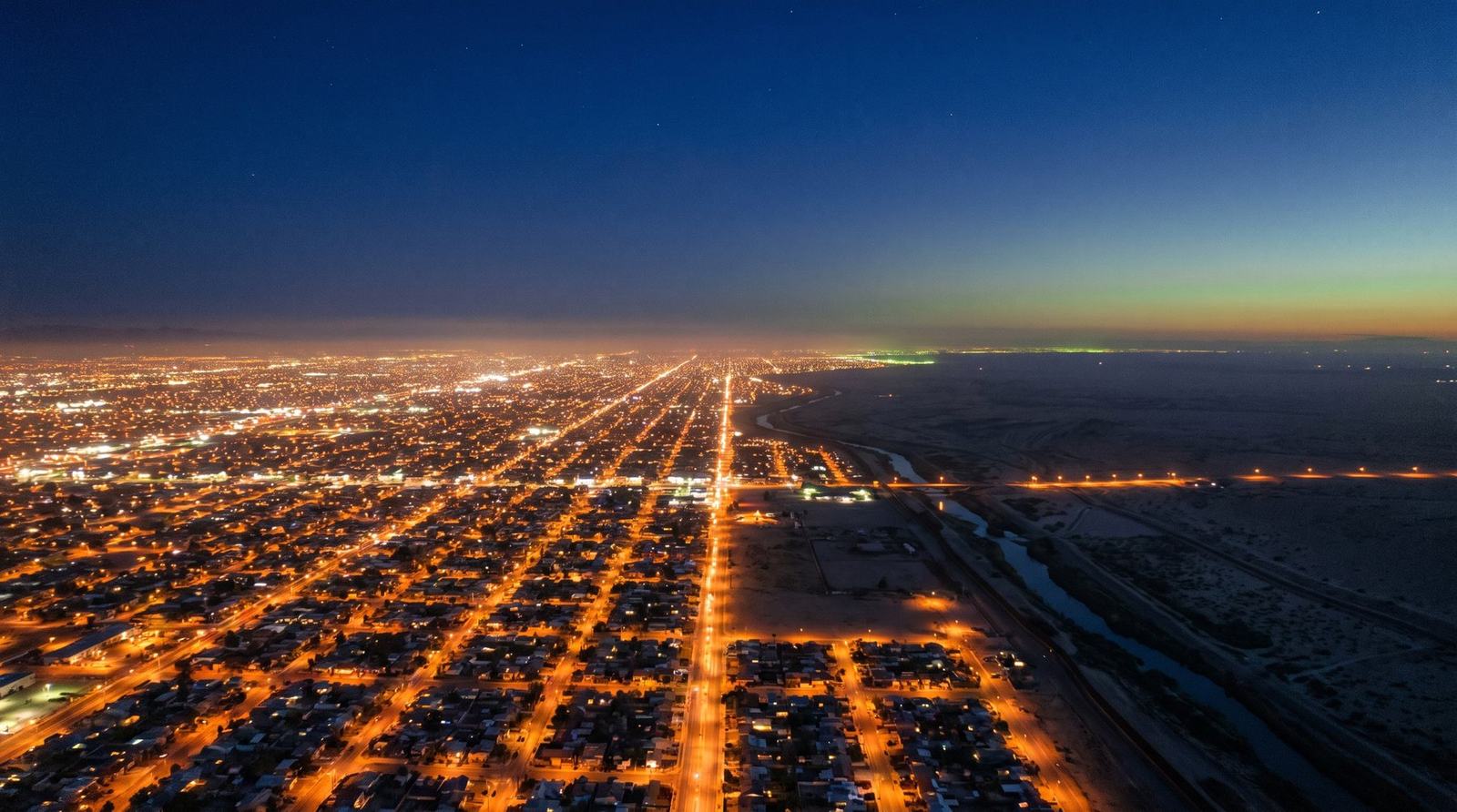 Ciudad fronteriza de noche, luces encendidas
